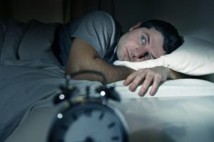 Man in bed eyes opened, suffering insomnia and sleep disorder
