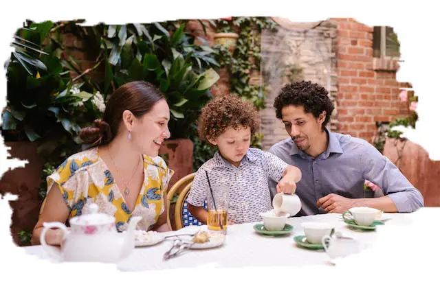photo of two parents playing tea party with their child