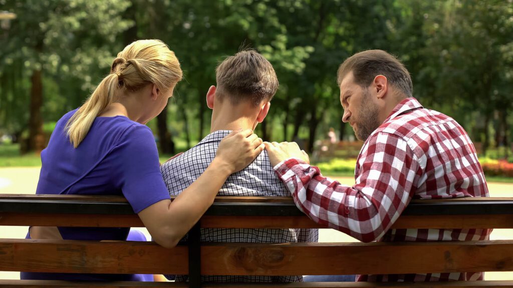 parents talking to their teenage kid on a park bench