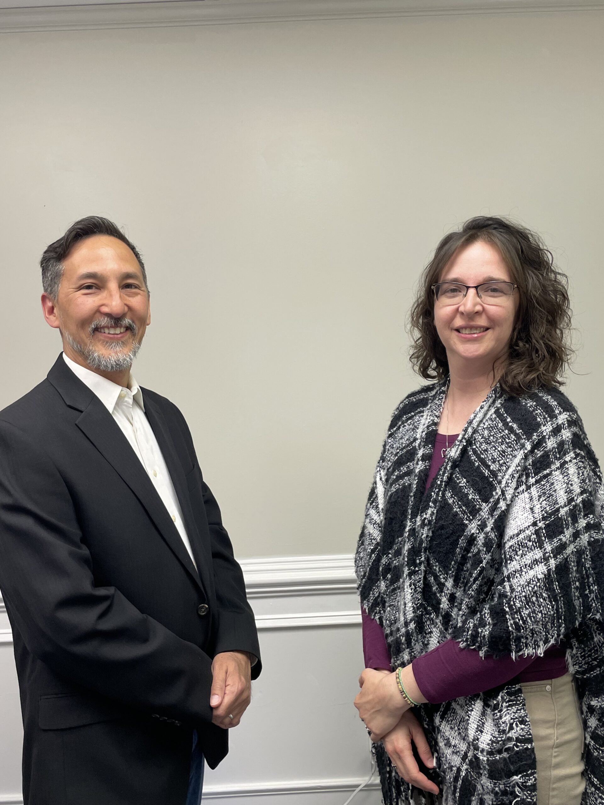 friendly male and female therapist of diverse backgrounds smiling at the camera, conveying warmth, trust, and professionalism.